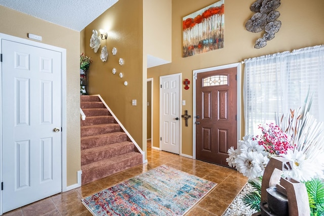 tiled entrance foyer featuring a textured ceiling and vaulted ceiling