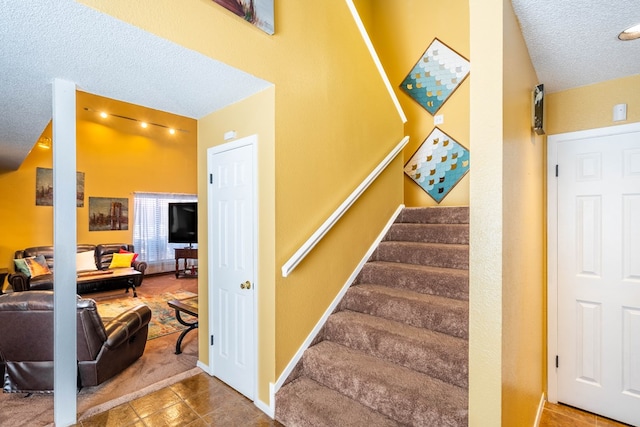 stairway with tile patterned flooring and a textured ceiling