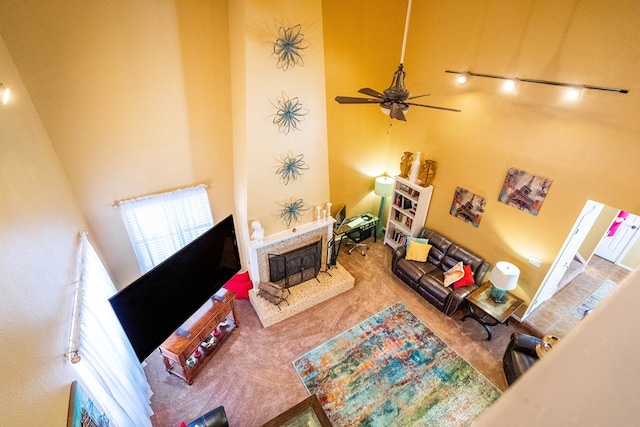 living room with carpet flooring, ceiling fan, and a towering ceiling