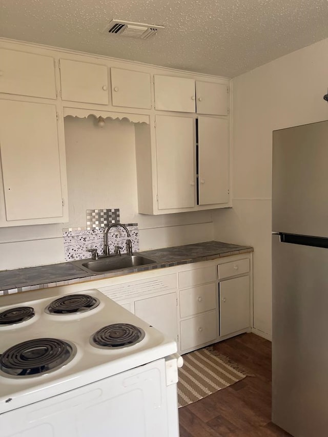 305 S Jackson Ave, Midland, TX 79701 - kitchen with freestanding refrigerator, white range with electric stovetop, dark wood-type flooring, and white cabinetry