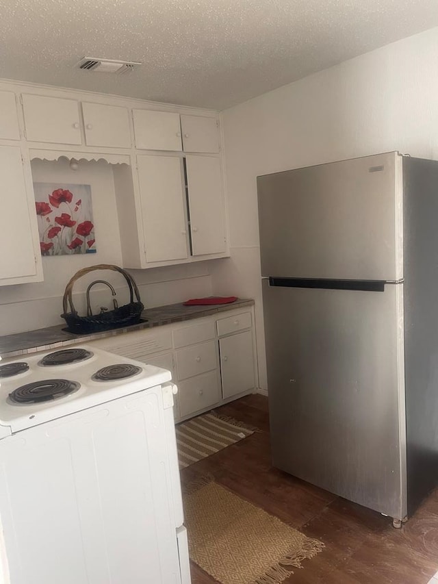 305 S Jackson Ave, Midland, TX 79701 - kitchen featuring freestanding refrigerator, dark wood-style flooring, white range with electric stovetop, white cabinetry, and a textured ceiling