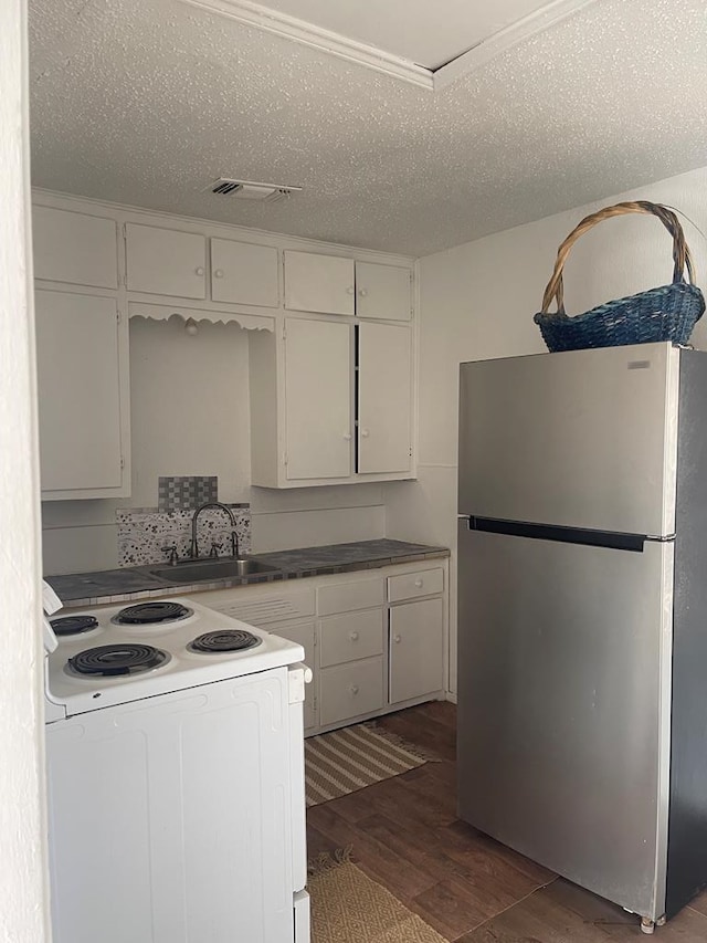 305 S Jackson Ave, Midland, TX 79701 - kitchen with freestanding refrigerator, white electric range oven, dark wood-type flooring, white cabinets, and a textured ceiling