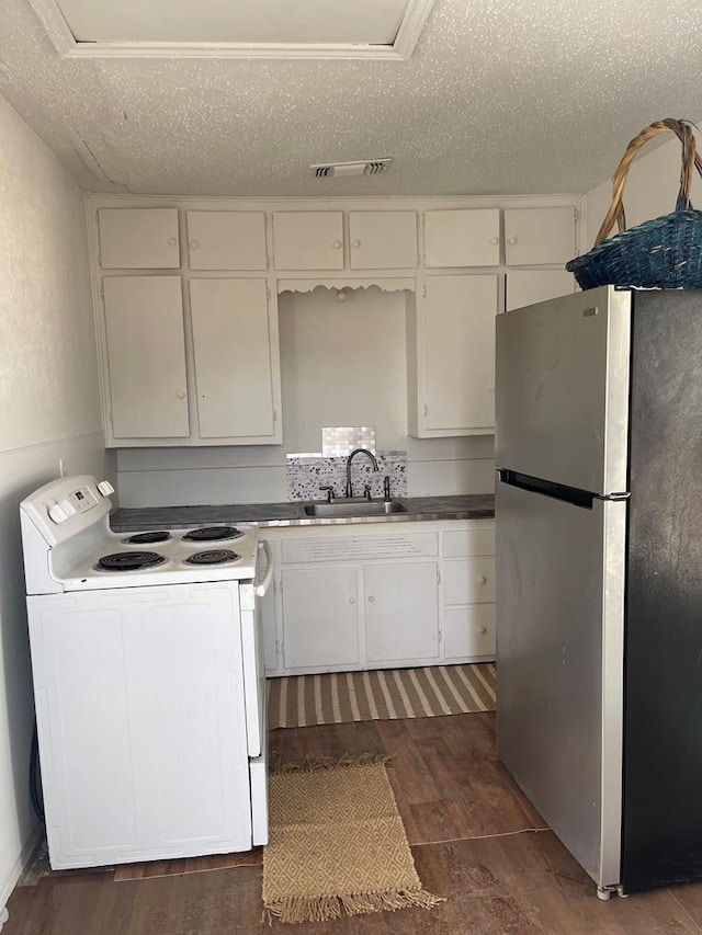 305 S Jackson Ave, Midland, TX 79701 - kitchen with freestanding refrigerator, electric stove, dark wood finished floors, white cabinets, and a textured ceiling