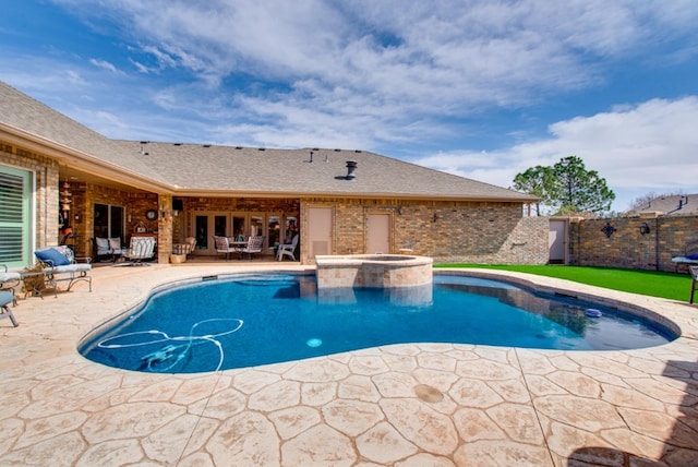 view of swimming pool featuring a pool with connected hot tub, fence, and a patio