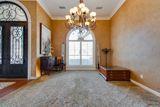 carpeted foyer with a notable chandelier, baseboards, visible vents, and crown molding