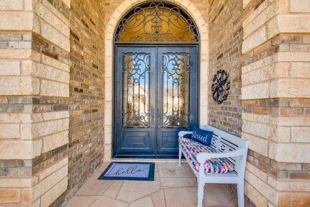 property entrance featuring french doors and brick siding