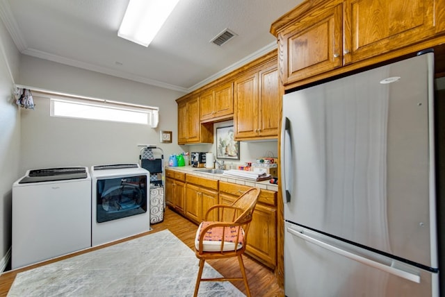 kitchen with tile countertops, separate washer and dryer, visible vents, light wood-style floors, and freestanding refrigerator