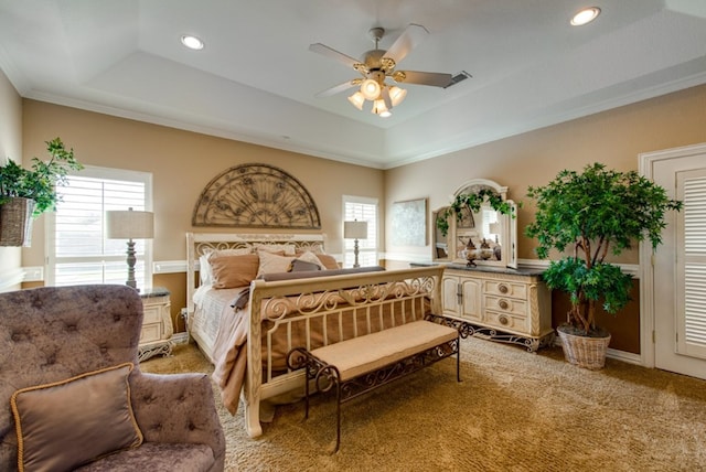 carpeted bedroom featuring a raised ceiling, multiple windows, and visible vents