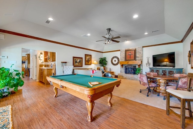 recreation room featuring visible vents, light wood-style floors, vaulted ceiling, a brick fireplace, and crown molding