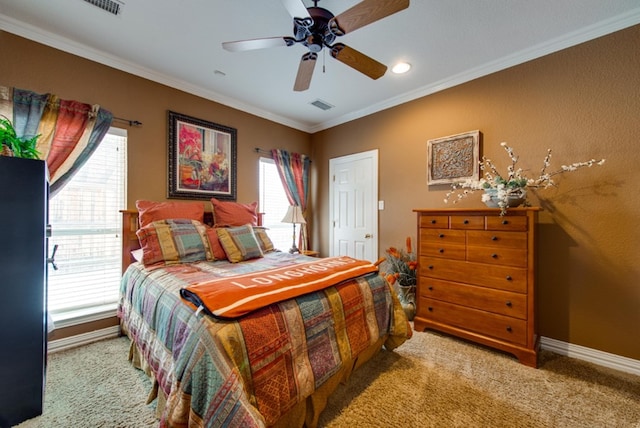 carpeted bedroom with a ceiling fan, visible vents, baseboards, and crown molding