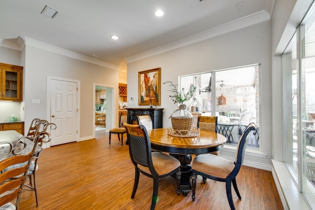 dining room with recessed lighting, crown molding, light wood-style flooring, and baseboards