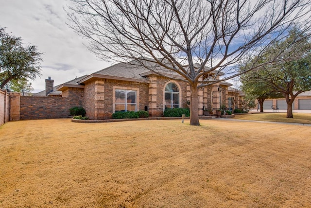 view of front of house with a chimney, fence, and a front yard