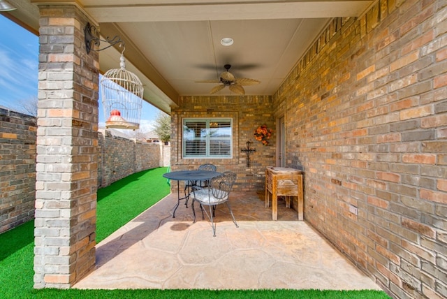 view of patio with a ceiling fan, outdoor dining space, and fence