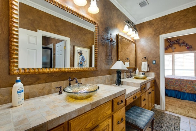 ensuite bathroom with double vanity, crown molding, visible vents, and a sink