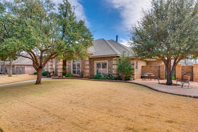 view of front of home featuring brick siding, a patio area, fence, and a front yard