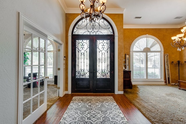 foyer with french doors, visible vents, a notable chandelier, and wood finished floors