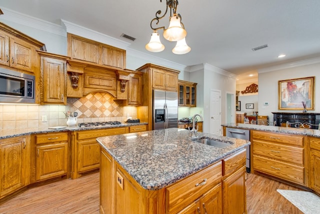 kitchen with visible vents, a center island with sink, appliances with stainless steel finishes, and a sink