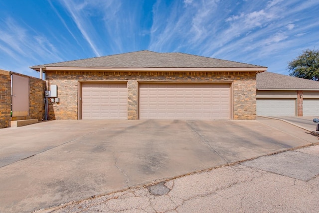 view of front facade with a garage, roof with shingles, and brick siding