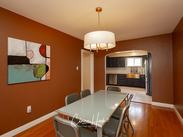 1700 Holloway Ave, Midland, TX 79701 - dining area with arched walkways, light wood-style floors, and a chandelier