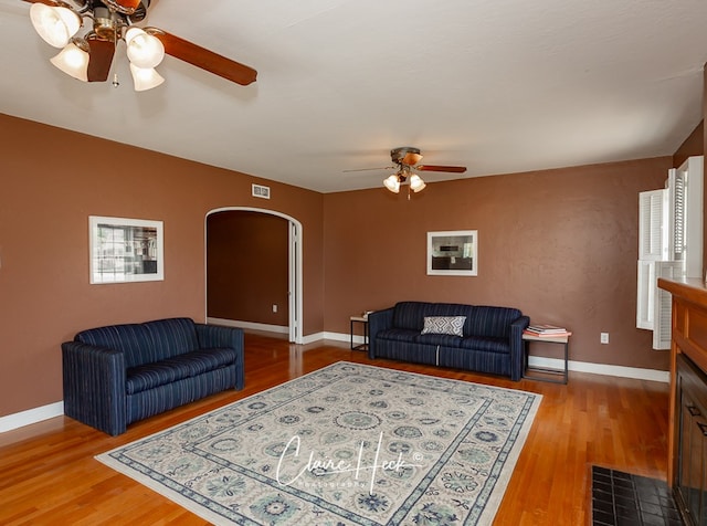 1700 Holloway Ave, Midland, TX 79701 - living room featuring ceiling fan, arched walkways, wood finished floors, and a fireplace with flush hearth