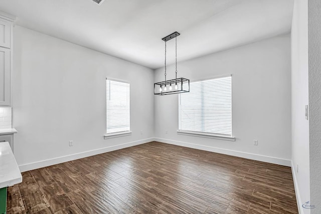 2200 S County Rd 1059, Midland, TX 79706 - unfurnished dining area with a notable chandelier, dark wood finished floors, and baseboards