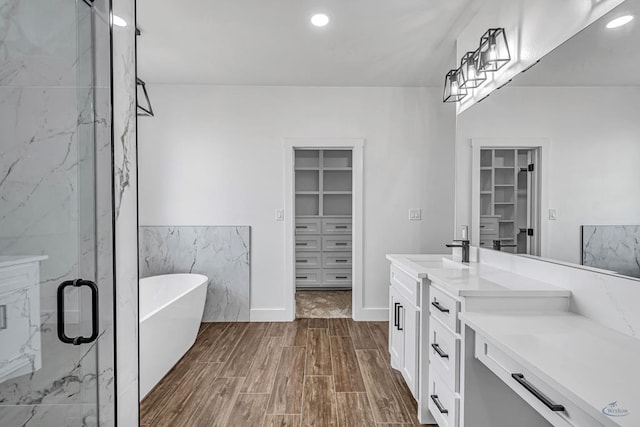 2200 S County Rd 1059, Midland, TX 79706 - full bathroom featuring a spacious closet, a marble finish shower, a freestanding tub, wood finished floors, and vanity