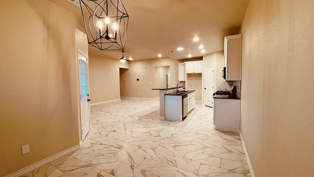 kitchen featuring hanging light fixtures, an island with sink, white cabinetry, ceiling fan, and sink