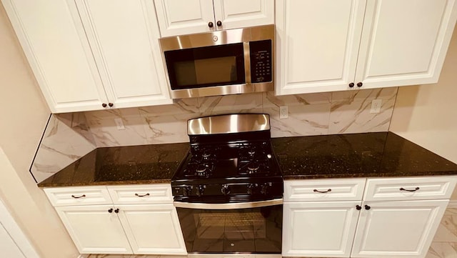 kitchen featuring black range with gas cooktop, white cabinetry, dark stone counters, and backsplash