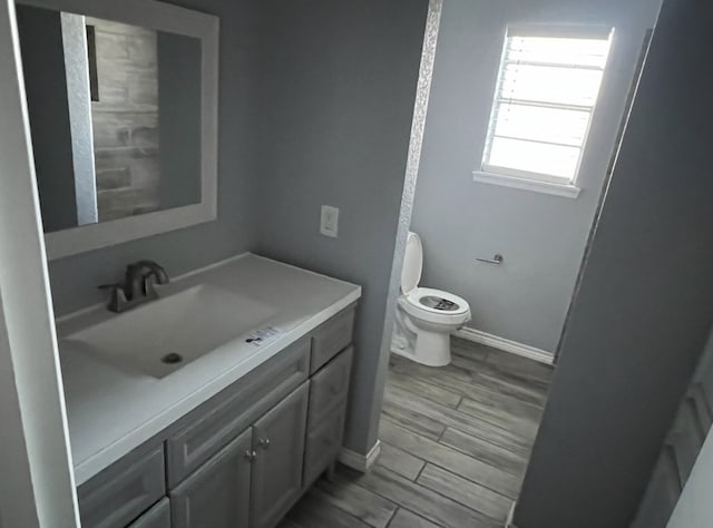 bathroom with wood tiled floor, baseboards, vanity, and toilet