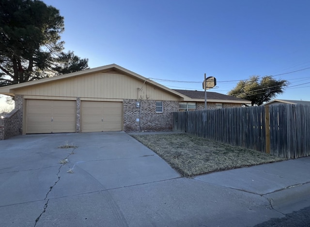 view of front of property featuring concrete driveway, brick siding, fence, and an attached garage