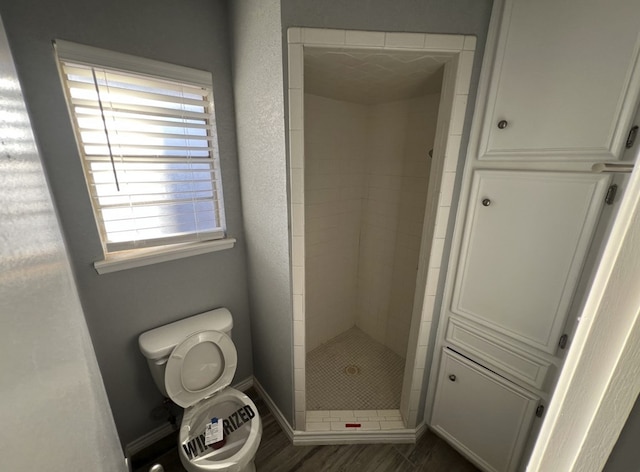 full bathroom with a shower stall, toilet, and baseboards