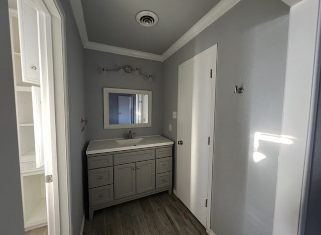 bathroom featuring vanity, wood finished floors, visible vents, and crown molding