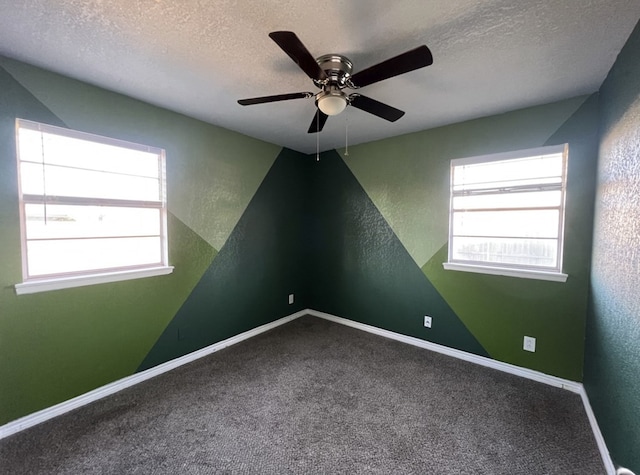 carpeted spare room featuring a ceiling fan, baseboards, a textured ceiling, and a textured wall