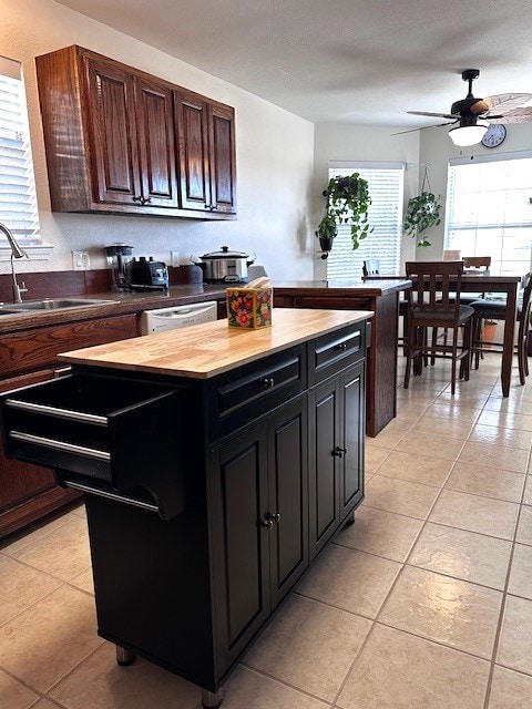 kitchen featuring wood counters, stainless steel dishwasher, ceiling fan, sink, and light tile patterned flooring