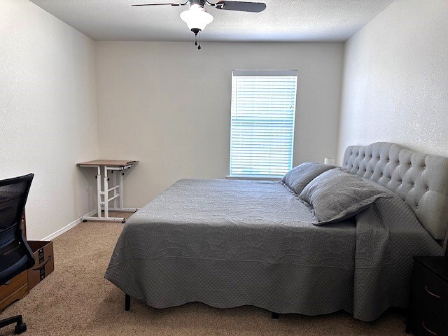 bedroom with carpet flooring, ceiling fan, and a textured ceiling