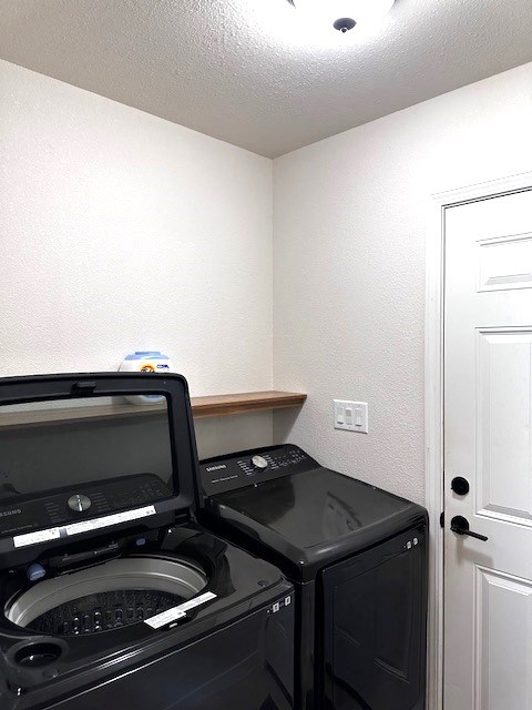 laundry area with independent washer and dryer and a textured ceiling