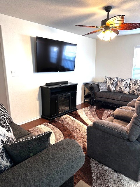 living room with ceiling fan, dark hardwood / wood-style floors, and a textured ceiling