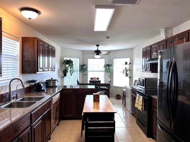 kitchen with dark brown cabinets, sink, light tile patterned floors, and black appliances