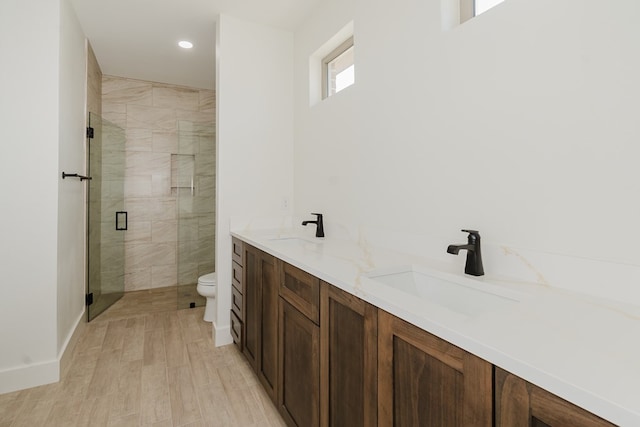 bathroom with wood-type flooring, vanity, toilet, and a shower with door