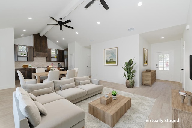 living room with vaulted ceiling with beams, ceiling fan, and light wood-type flooring