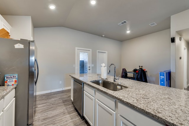 1109 Cajun St, Odessa, TX 79765 - kitchen featuring appliances with stainless steel finishes, white cabinets, light wood finished floors, lofted ceiling, and light stone countertops