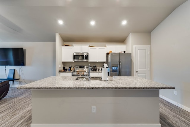 1109 Cajun St, Odessa, TX 79765 - kitchen with appliances with stainless steel finishes, a center island with sink, white cabinetry, wood finished floors, and light stone counters