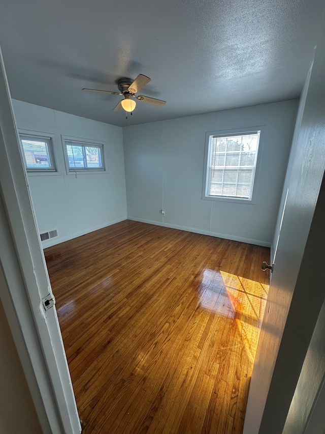 empty room featuring hardwood / wood-style floors, ceiling fan, and a textured ceiling