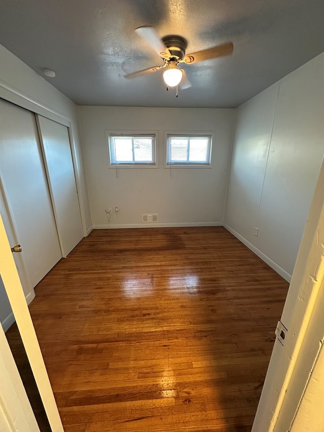 unfurnished bedroom with a textured ceiling, hardwood / wood-style flooring, and ceiling fan