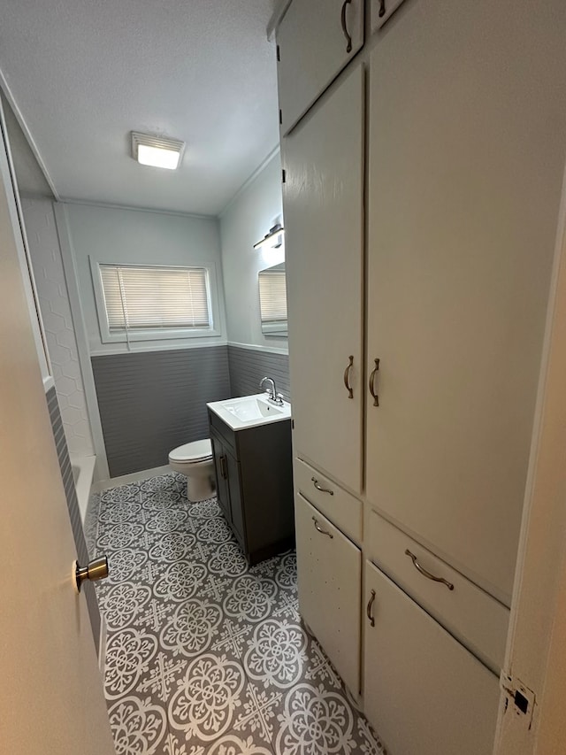 bathroom featuring a textured ceiling, vanity, toilet, and walk in shower