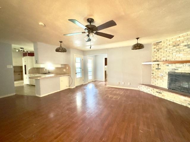 unfurnished living room featuring a fireplace, dark hardwood / wood-style flooring, and ceiling fan