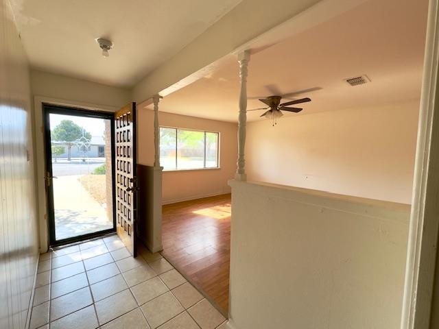 entryway with light wood-type flooring, ornate columns, plenty of natural light, and ceiling fan