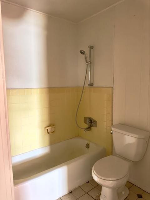 bathroom featuring tile patterned flooring, toilet, and tile walls