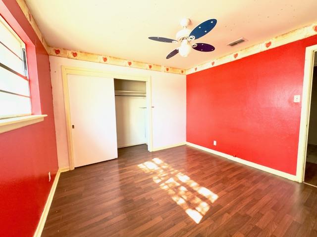 unfurnished bedroom with ceiling fan, a closet, and dark hardwood / wood-style floors