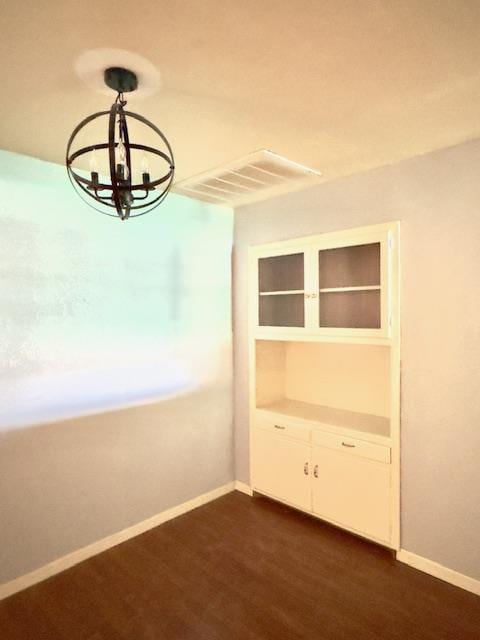 unfurnished room featuring a chandelier and dark hardwood / wood-style flooring